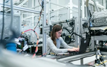 Technician inspecting components at a production workbench under bright light
